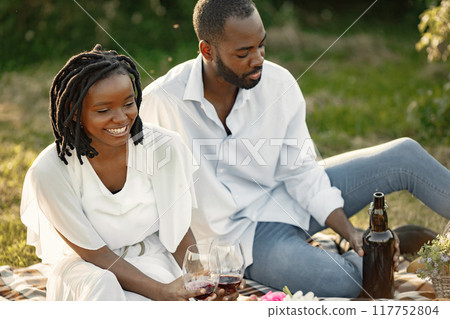Carefree, relaxed couple enjoying the picnic together. Man poring wine into glass. 117752804