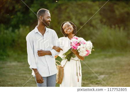 Young African couple in romantic embrace in a field. Young lovers in a field with flowers. 117752805