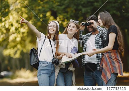 Adventure, travel, tourism, hike and people concept. Group of smiling friends in a forest. Man with binocularus. Adventure, travel, tourism, hike and people concept. Group of smiling friends in a forest. Man with binocularus. 117752823
