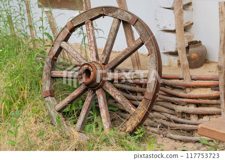 Retro wooden wheel. Old wooden wheel in nature background. Village life. Retro wooden wheel. Old wooden wheel in nature background. Village life. 117753723