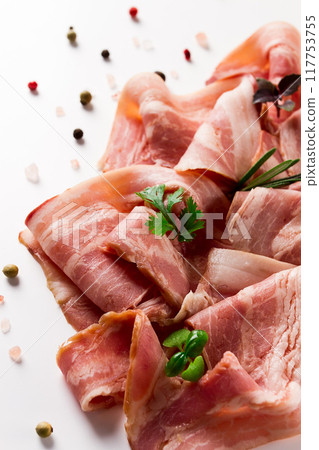 Raw bacon, sliced, with micro greenery and spices, on a white background, close-up, 117753755