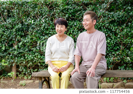 Senior couple sitting on a bench Senior couple sitting on a bench 117754456