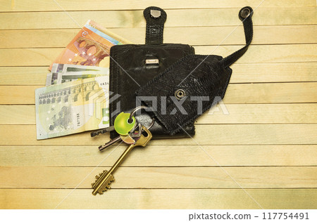 Leather purse with keys lie on a wooden surface Leather purse with keys lie on a wooden surface 117754491