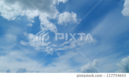 Blue clear sky with white cumulus and cirrus spindrift clouds background. Light white cirrus clouds in blue sky on a summer day. Timelapse. 117754643