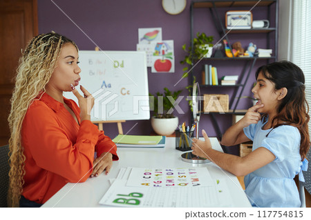 Educator Teaching Young Student in Colorful Classroom Educator Teaching Young Student in Colorful Classroom 117754815
