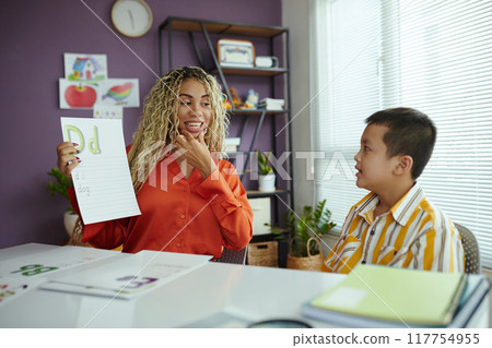 Smiling Woman Teaching Boy in Classroom Setting 117754955
