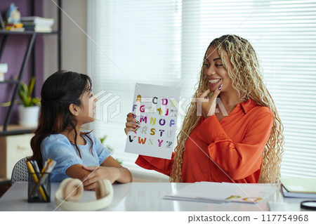 Teacher Showing Alphabet Chart to Smiling Student in Classroom 117754968