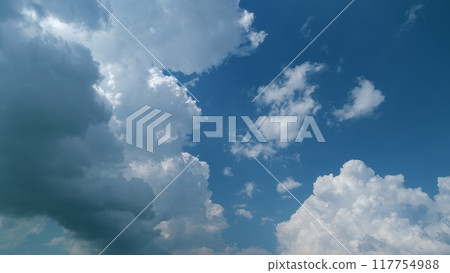 Cumulonimbus clouds forming in sky. White clouds in a blue sky. Sun rays before thunder rain storm or hurricane. Timelapse. 117754988
