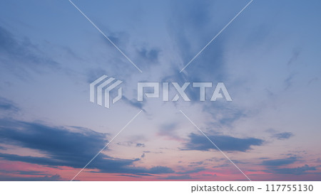 Sun below the horizon and clouds in the fiery dramatic sky. Cirrus clouds illuminated by sunbeams. Timelapse. 117755130