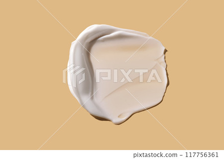 A smear of white cream on a beige background. 117756361