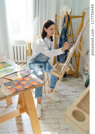 A Joyful Artist Proudly Showcasing Their Colorful Paint Brushes in a Bright and Inspiring Studio Environment 117756449