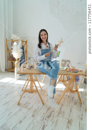 A Joyful Artist Proudly Showcasing Their Colorful Paint Brushes in a Bright and Inspiring Studio Environment 117756451