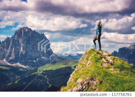 Girl on the peak, flowers and green grass in alpine mountains Girl on the peak, flowers and green grass in alpine mountains 117756761
