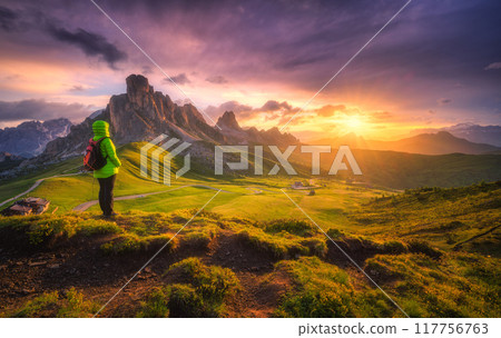 Woman with backpack and beautiful alpine mountain peaks at sunse Woman with backpack and beautiful alpine mountain peaks at sunse 117756763
