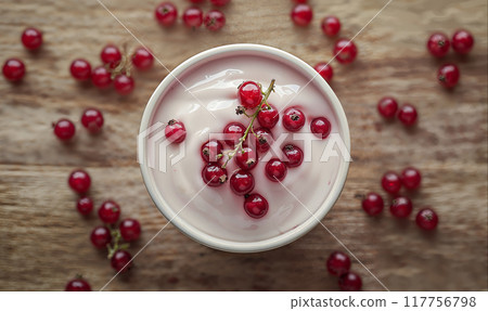 Greek yogurt with red currant berries on wooden table with copy space, top view 117756798