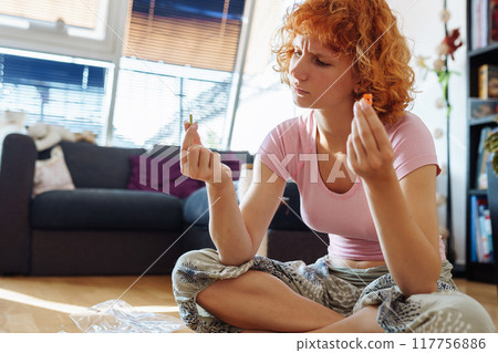 teenage girl assembles construction set according to instructions sitting on floor in room 117756886