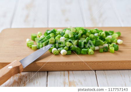 Slicing fresh spring onions on a cutting board , selective focus. Slicing fresh spring onions on a cutting board , selective focus. 117757143