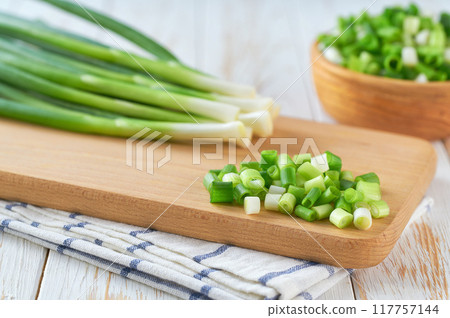 Chopped fresh green onions on a white table . Copy space for text. Chopped fresh green onions on a white table . Copy space for text. 117757144