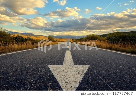 A long stretch of road leading to distant mountains, bathed in warm sunset light with dramatic clouds overhead A long stretch of road leading to distant mountains, bathed in warm sunset light with dramatic clouds overhead 117757467
