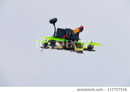 Military FPV drone, low cost reconnaissance aircraft for modern warfare, close-up on gray sky background Military FPV drone, low cost reconnaissance aircraft for modern warfare, close-up on gray sky background 117757556