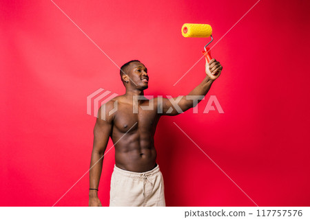 Happy construction worker holding paint roller performing interior renovation with optimism. 117757576