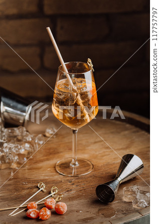 Elegant cocktail on a rustic wooden table with garnishes and ice, perfect for upscale bars 117757797
