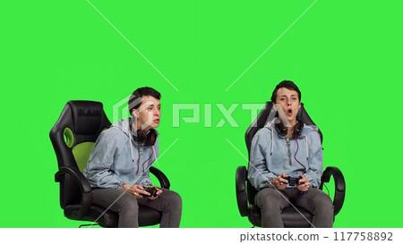 Gamer feeling angry about losing video games competition against greenscreen, playing on console with controller and gaming setup. Irritated displeased woman lost shooter action. Camera B. 117758892