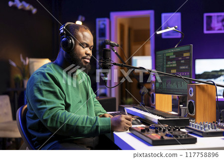 Skilled musician artist creating a new track in his home studio, thinking about verses to fit the rhymes and rhythm. Composer singer writing down lyrics to create a soundtrack, acoustical engineering. 117758896