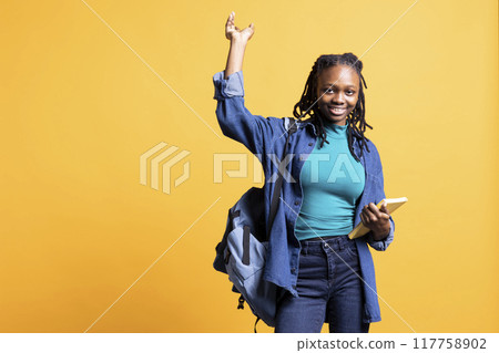 Portrait of upbeat person with book in hands pointing towards empty copy space, isolated over studio background. Cheerful bookworm holding novel, pointing finger off camera Portrait of upbeat person with book in hands pointing towards empty copy space, isolated over studio background. Cheerful bookworm holding novel, pointing finger off camera 117758902
