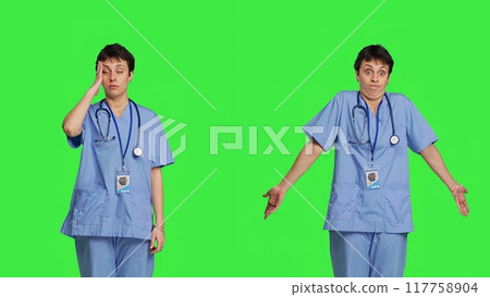 Medical assistant having a headache and doing confusion symbol, standing against greenscreen backdrop. Nurse deals with a migraine and burnout, shows i dont know sign and being clueless. Camera B. 117758904