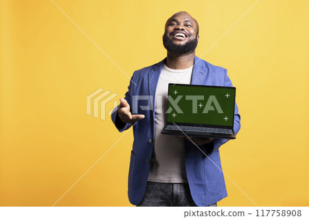 Portrait of relaxed carefree man pointing towards green screen laptop, doing endorsement. Delighted tech reviewer giving positive feedback to chroma key notebook, isolated over studio background 117758908