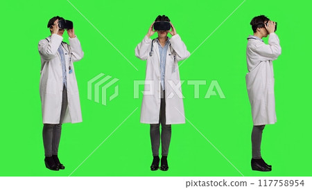 Physician uses virtual reality interactive lens on headset in studio, checks diagnosis with artificial intelligence three dimensional tool. Doctor works with vr glasses against greenscreen. Camera A. 117758954