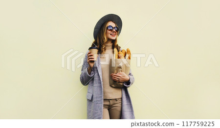 Happy bakery buyer young woman holding grocery shopping paper bag with bread baguette drinks coffee Happy bakery buyer young woman holding grocery shopping paper bag with bread baguette drinks coffee 117759225