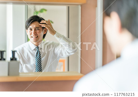 Young Asian man wiping his hairline in the bathroom (thinning hair, hair loss, AGA, hair loss) Young Asian man wiping his hairline in the bathroom (thinning hair, hair loss, AGA, hair loss) 117763215