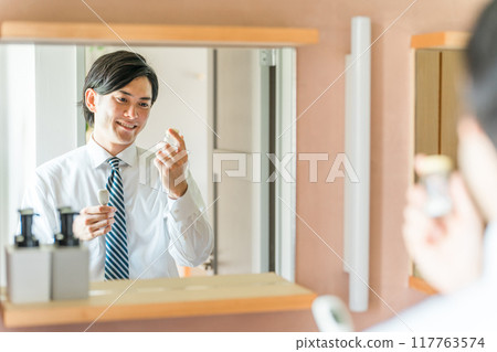 A young Asian male businessman reading the ingredients of medicines and supplements in the bathroom A young Asian male businessman reading the ingredients of medicines and supplements in the bathroom 117763574