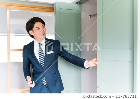 一位男性商人，是房屋建築商的規劃師/推銷員/顧問，展示了一個衣櫃 117763731