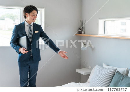 A businessman/hotel man introducing the bedroom A businessman/hotel man introducing the bedroom 117763737