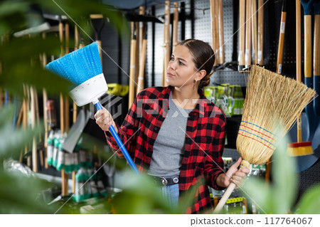Female farmer choosing broom in gardening store 117764067