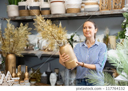 Woman selecting golden decorative plant in store 117764132