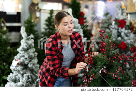 Young woman choosing christmas tree in store 117764172