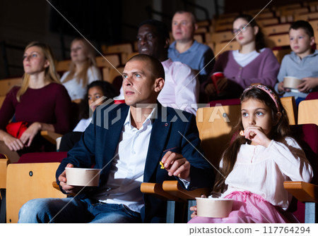 mother, father and their children sitting at film in auditorium 117764294