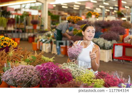 Young woman choosing bouquet of dried flowers Young woman choosing bouquet of dried flowers 117764334