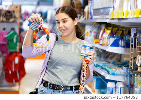 Young woman choosing toys for four-legged friend in pet shop 117764358