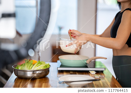 A cropped image of a female food blogger is cooking in front of the camera. A cropped image of a female food blogger is cooking in front of the camera. 117764415