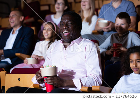 caucasian mother, african father and their children sitting at comedy in auditorium 117764520