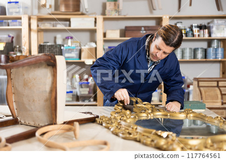 collected male restorer carefully covers carved wooden frame of antique mirror with layer of varnish collected male restorer carefully covers carved wooden frame of antique mirror with layer of varnish 117764561