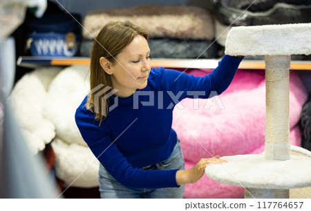 Woman choosing cat scratching post with fur platforms for cat 117764657