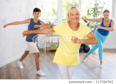 Happy old woman practicing dance positions during workout session Happy old woman practicing dance positions during workout session 117764762