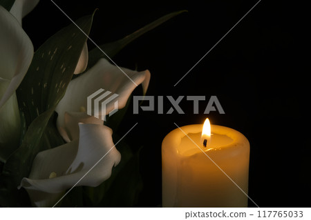Burning wax candle and white calla lily flowers in darkness Burning wax candle and white calla lily flowers in darkness 117765033