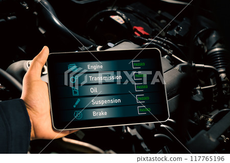 Mechanic checks car maintenance with wireless scan tool with car engine compartment background. 117765196